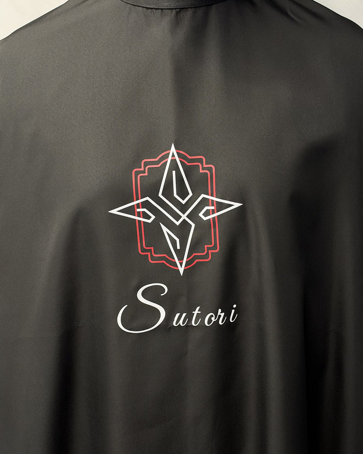 Sutori crest and name printed on the barber cape