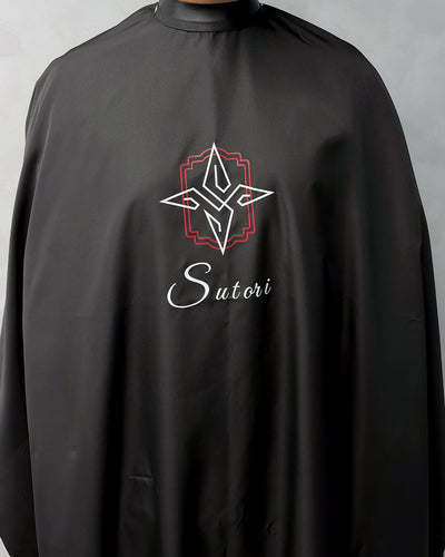 Black Sutori barber cape worn, from the front, with the Sutori crest and name