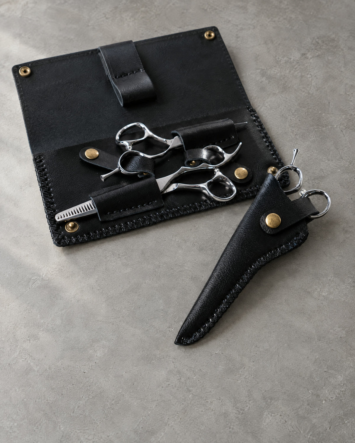 Double leather case and leather blade protector on grey microcement