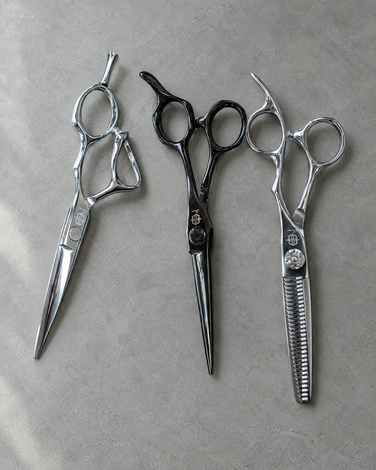 Shinobi, Zen and Kaze scissors side by side on grey microcement