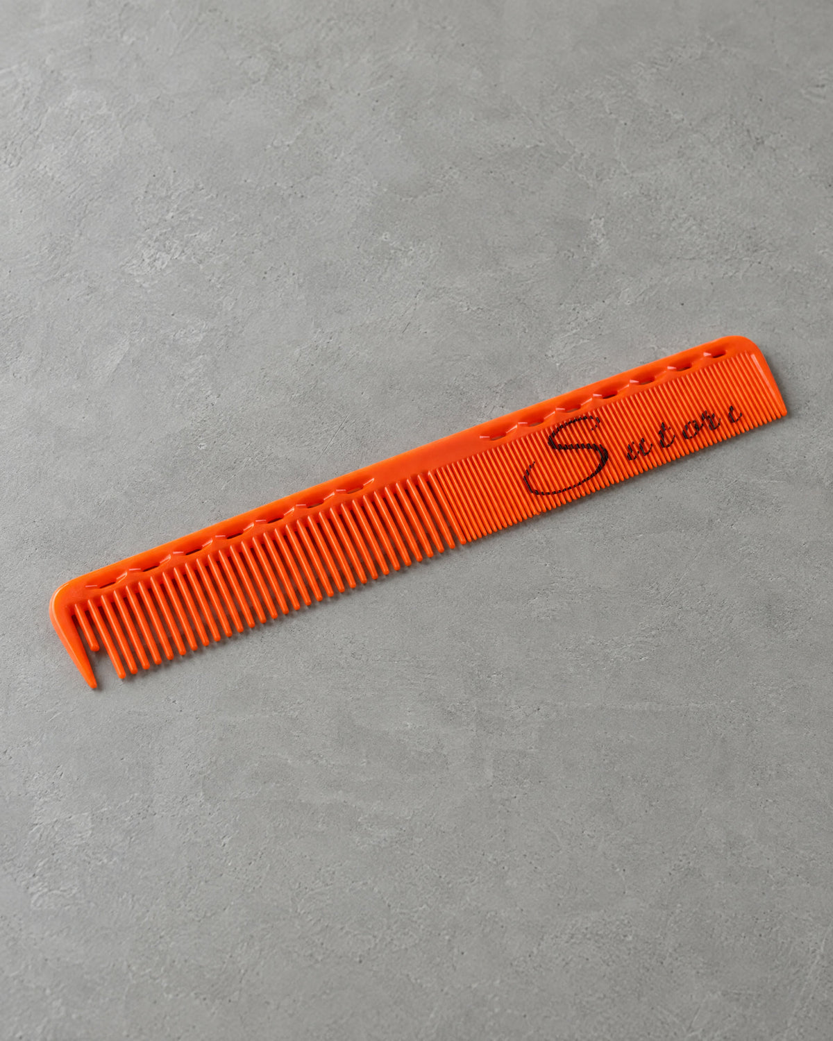 Orange Sutori cutting comb on grey microcement
